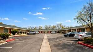 A motel with a central parking lot, multiple rooms, and a clear sky. - OYO Hotel San Antonio Near At&t Center (San Antonio)