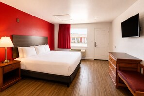 A hotel room with a bed, bedside table, lamp, TV, and a window with curtains. - OYO Hotel San Antonio Near At&t Center (San Antonio)