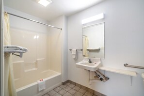 Un baño con bañera, lavabo, espejo y cortina de ducha.