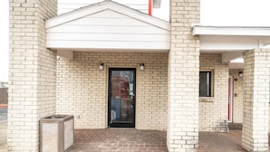 A building entrance with a brick facade, a black door, and a small window.