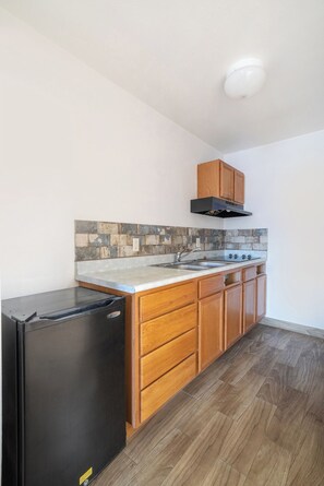 A compact kitchen with a refrigerator, stove, and wooden cabinets. - OYO Hotel San Antonio Near At&t Center (San Antonio)