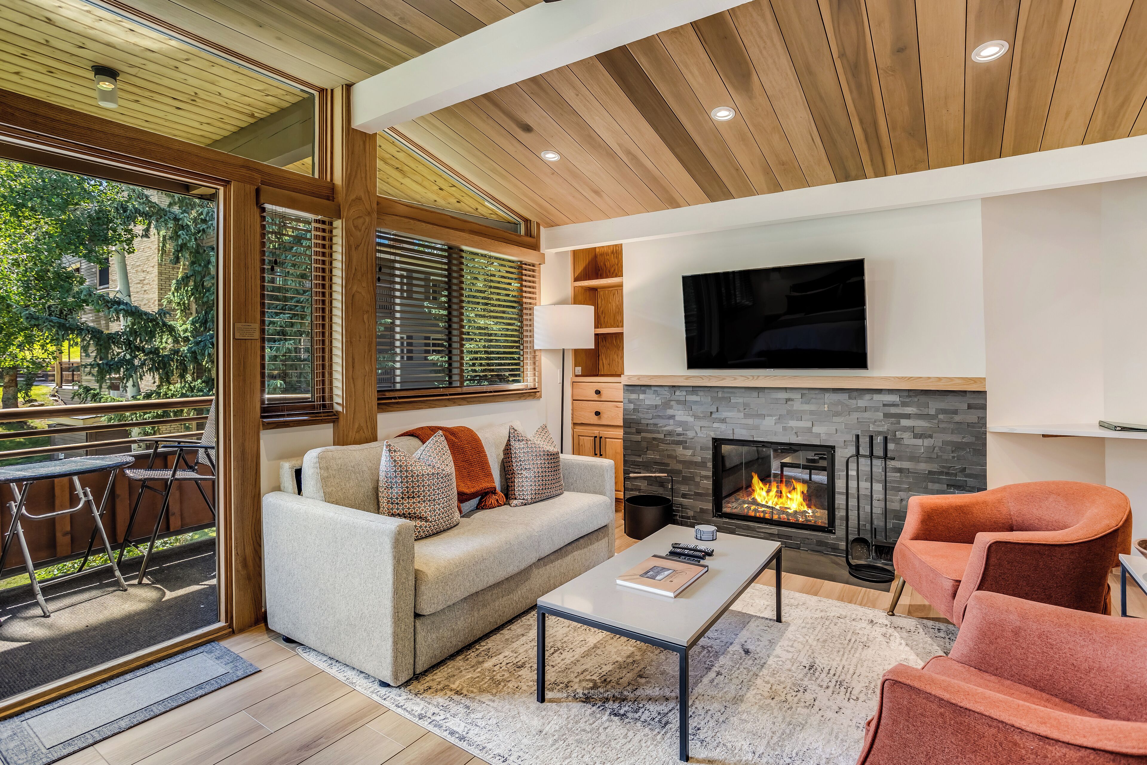 A modern living room with a fireplace, sofa, coffee table, and a TV mounted on the wall.