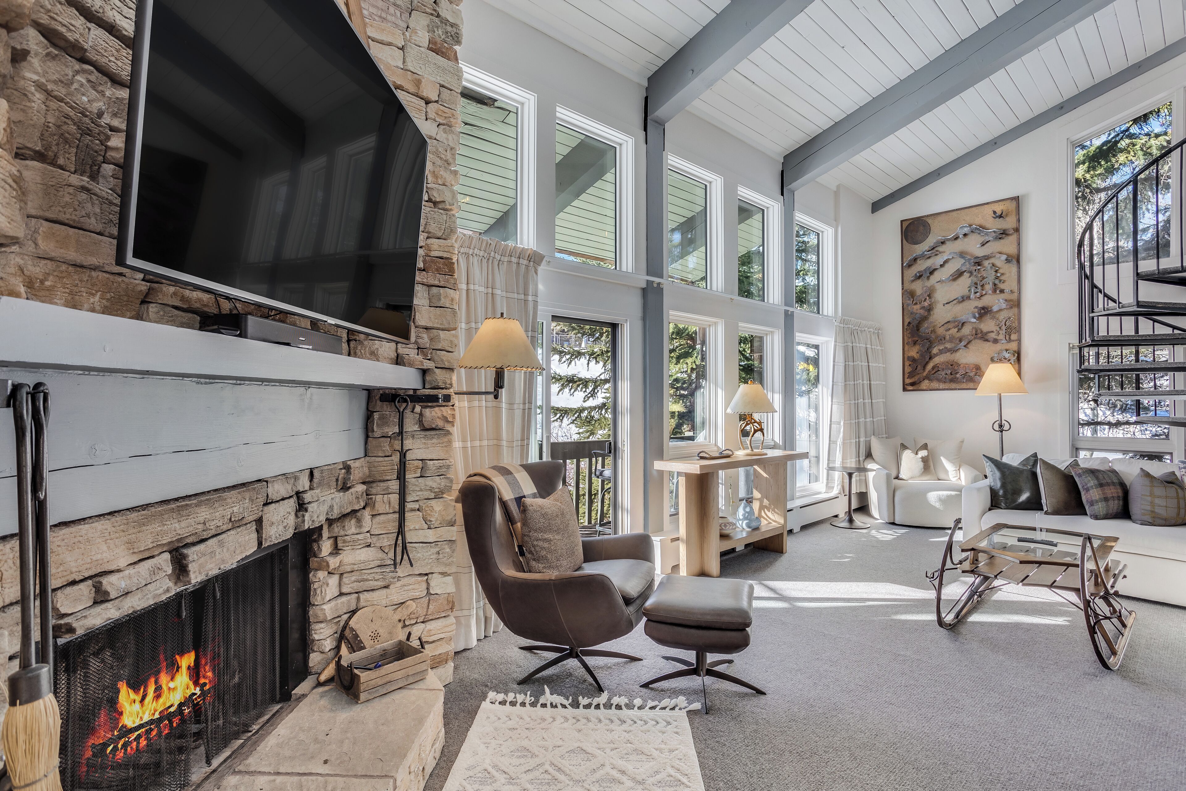 A modern living room with a stone fireplace, a large TV, and a cozy seating area.