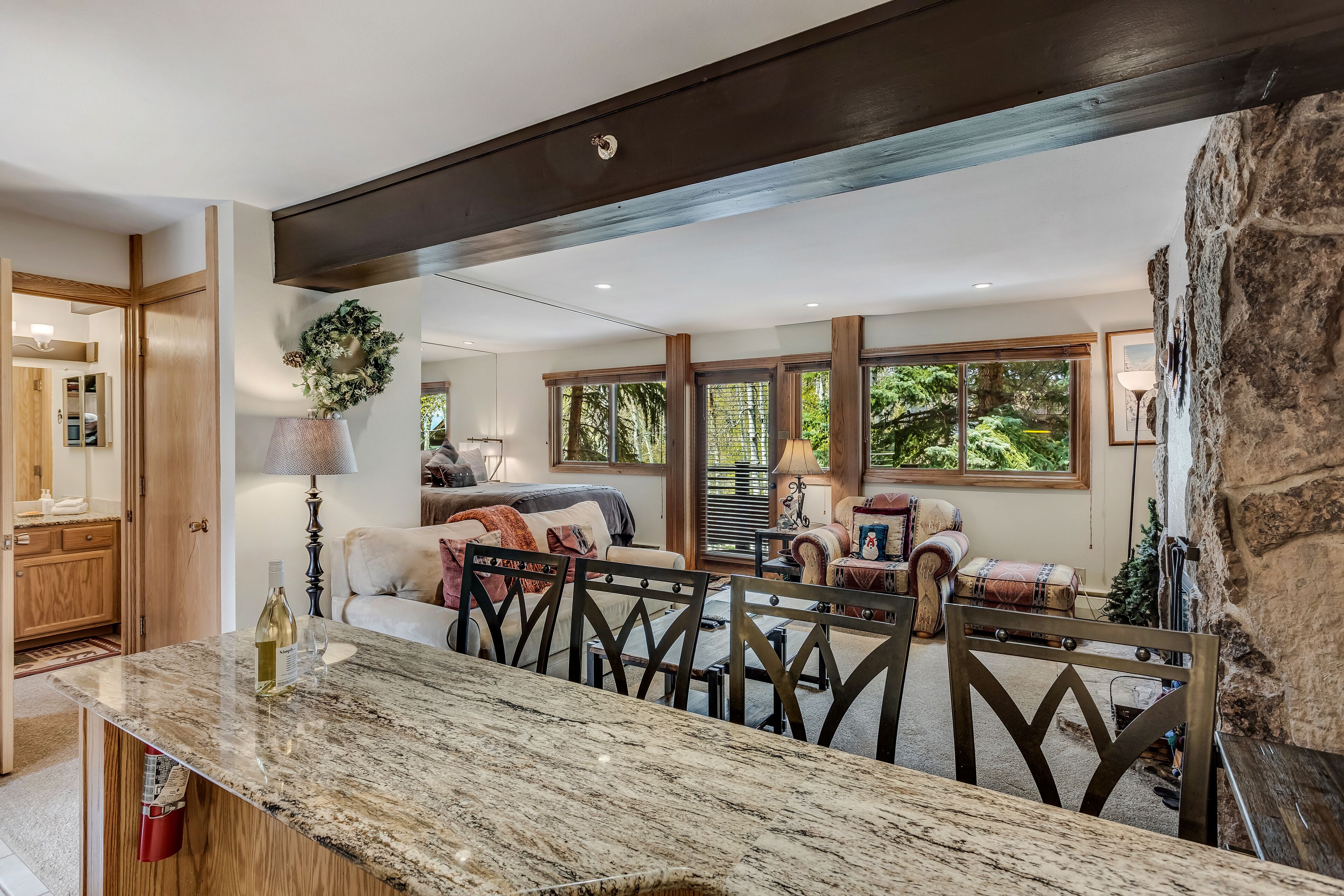 Un salón espacioso con una pared de acento de piedra, una mesa de comedor con sillas y una zona de estar acogedora con un sofá y sillones.