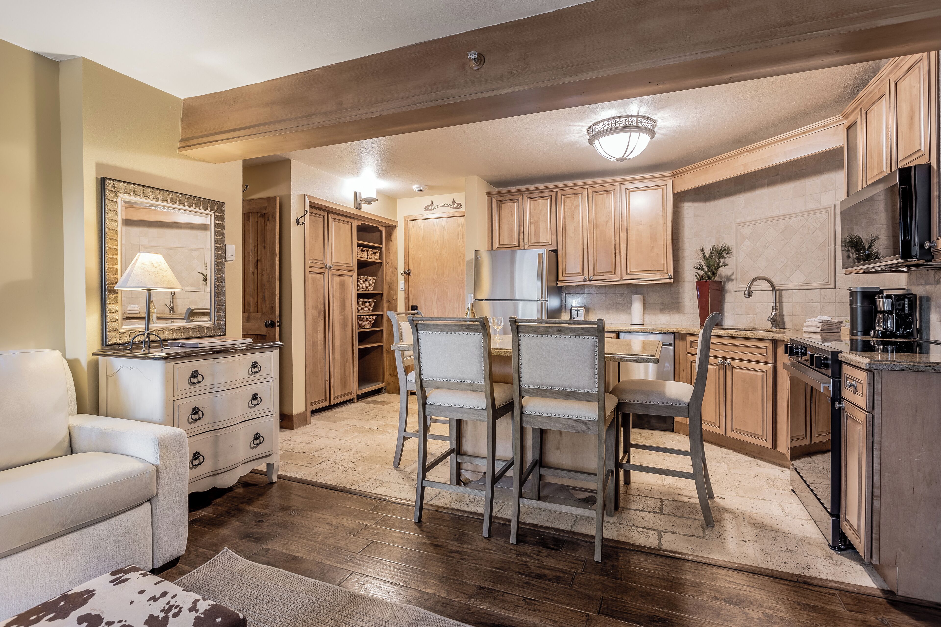 A spacious kitchen with wooden cabinets, a dining area with chairs, and a refrigerator.