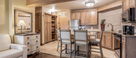 A spacious kitchen with wooden cabinets, a dining area with chairs, and a refrigerator.