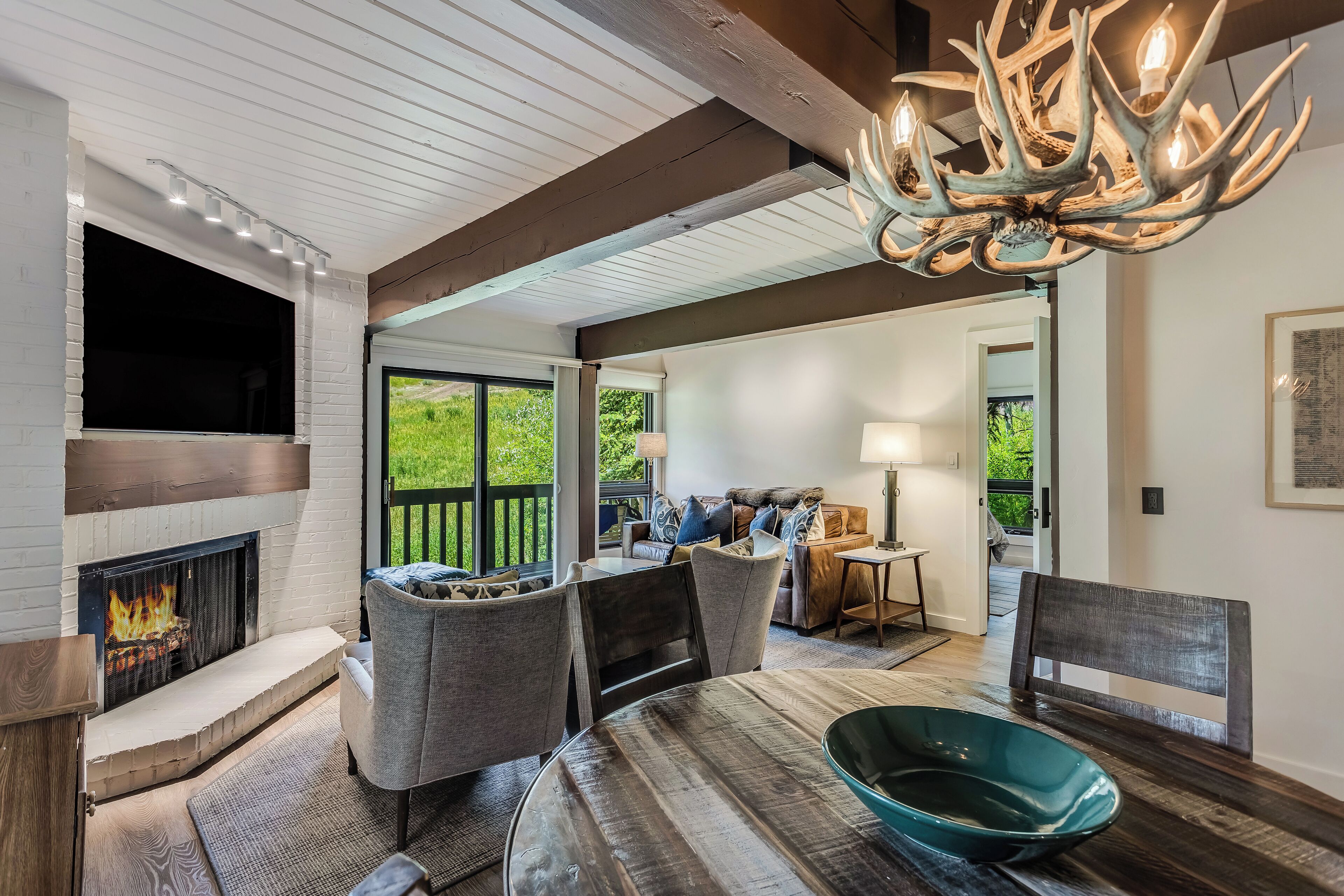 Un salon chaleureux avec une cheminée, des fauteuils confortables et une grande fenêtre.