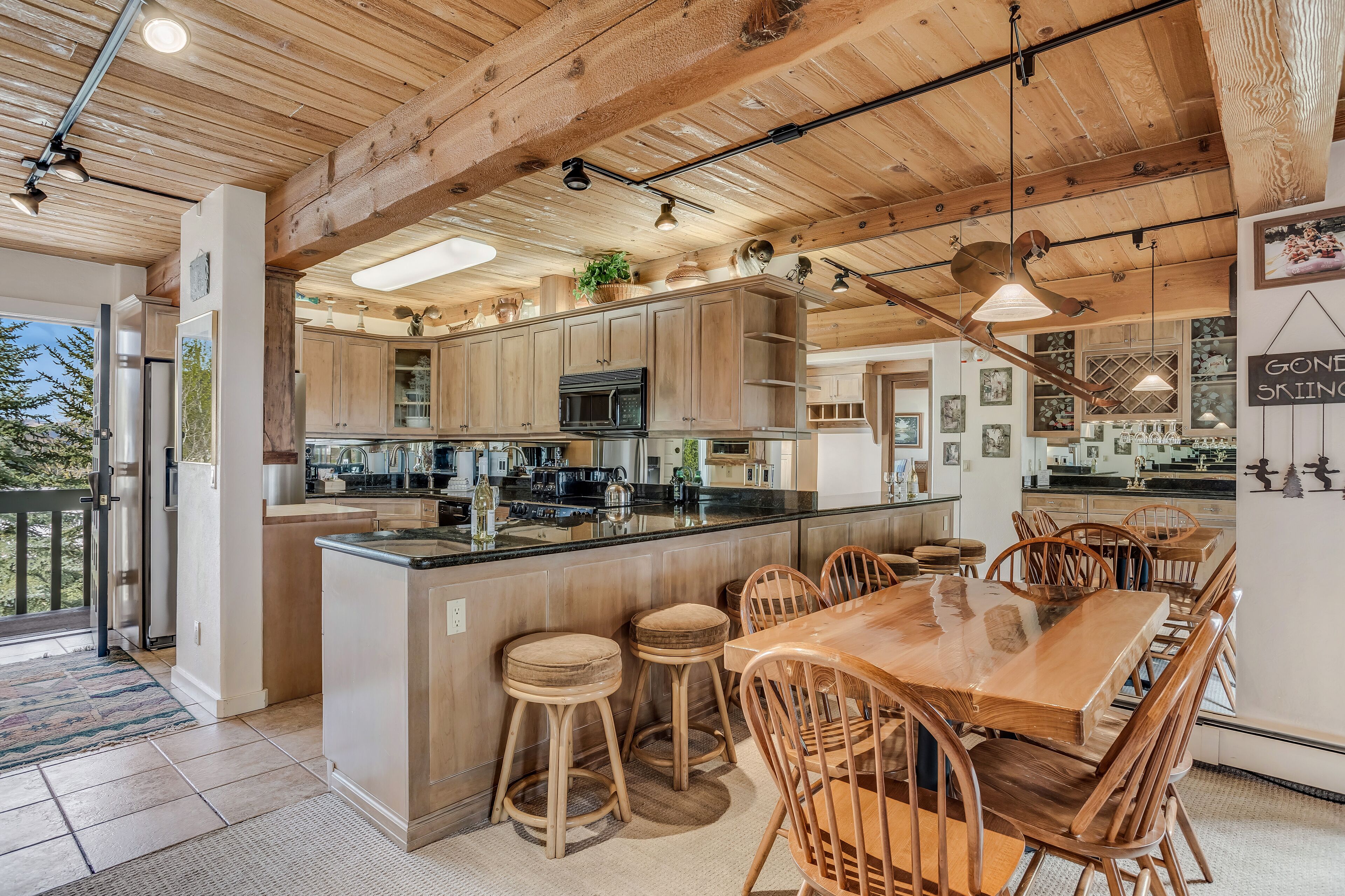 Una cocina amplia con armarios de madera, una isla central con taburetes y un comedor con sillas de madera.