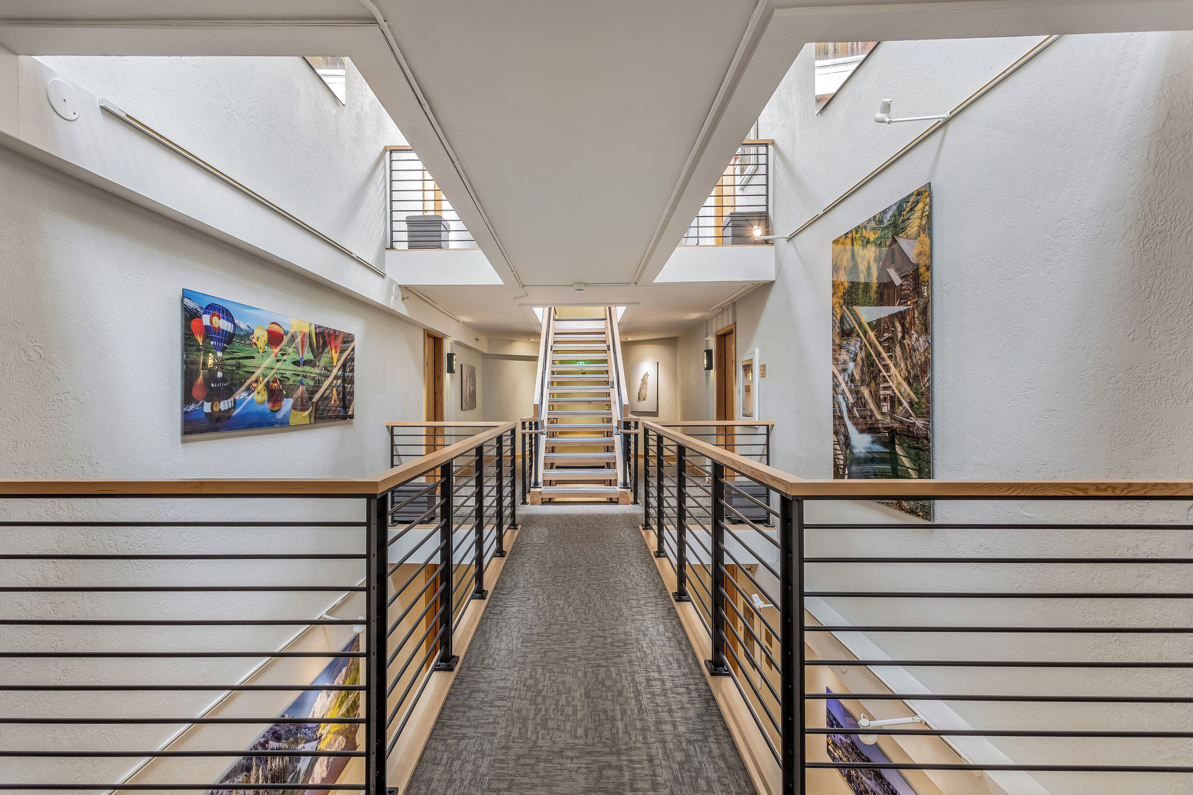 A modern interior with a central staircase, white walls, and artwork on the sides.