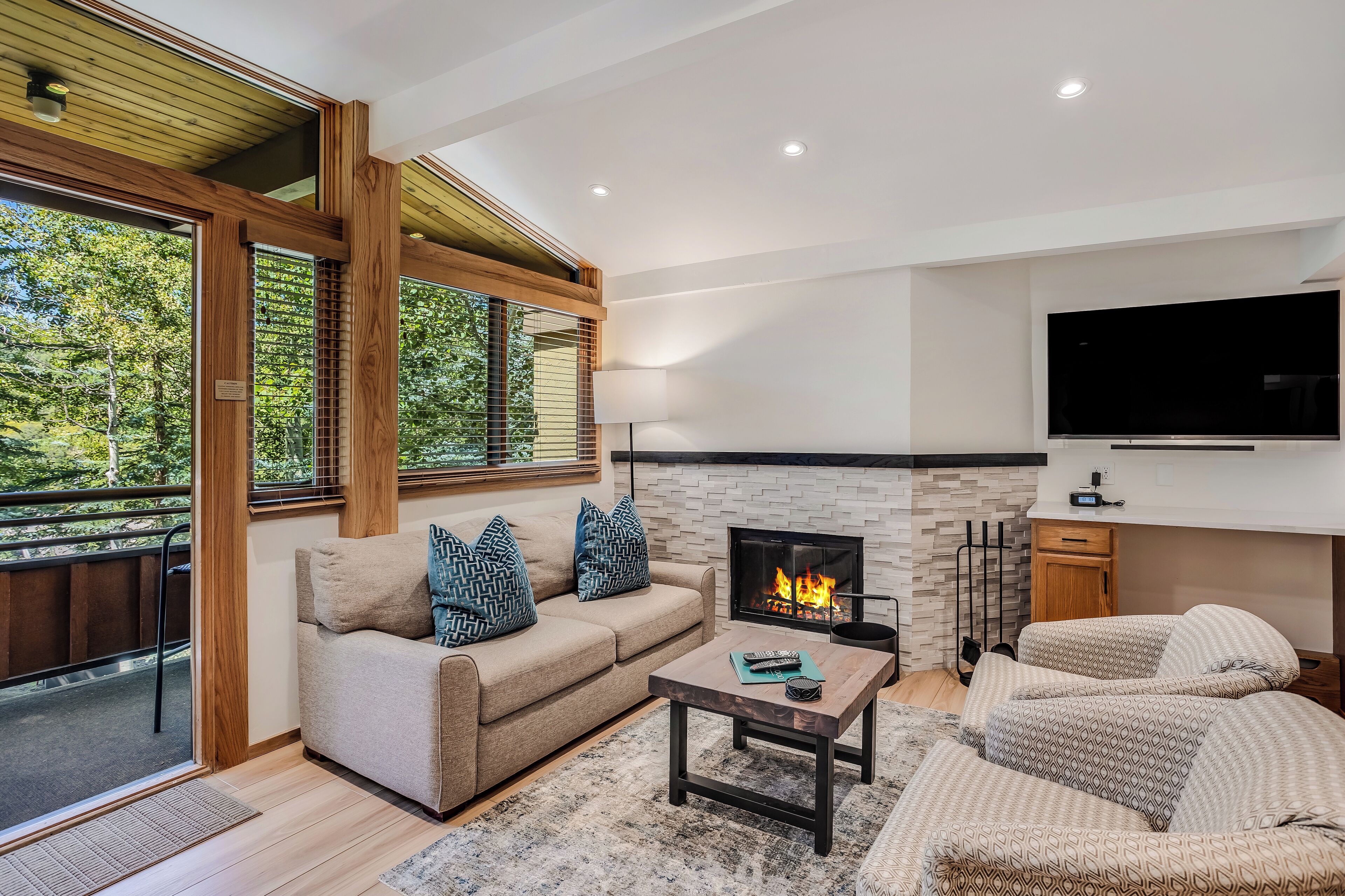 A modern living room with a fireplace, a sofa set, a coffee table, and a TV mounted on the wall.
