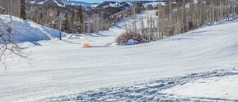 En snötäckt skidbacke med klar himmel och avlägsna berg i bakgrunden.
