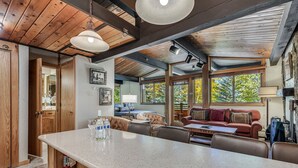Una cocina amplia con una isla grande, vigas de madera en el techo y ventanas grandes con vistas al exterior.