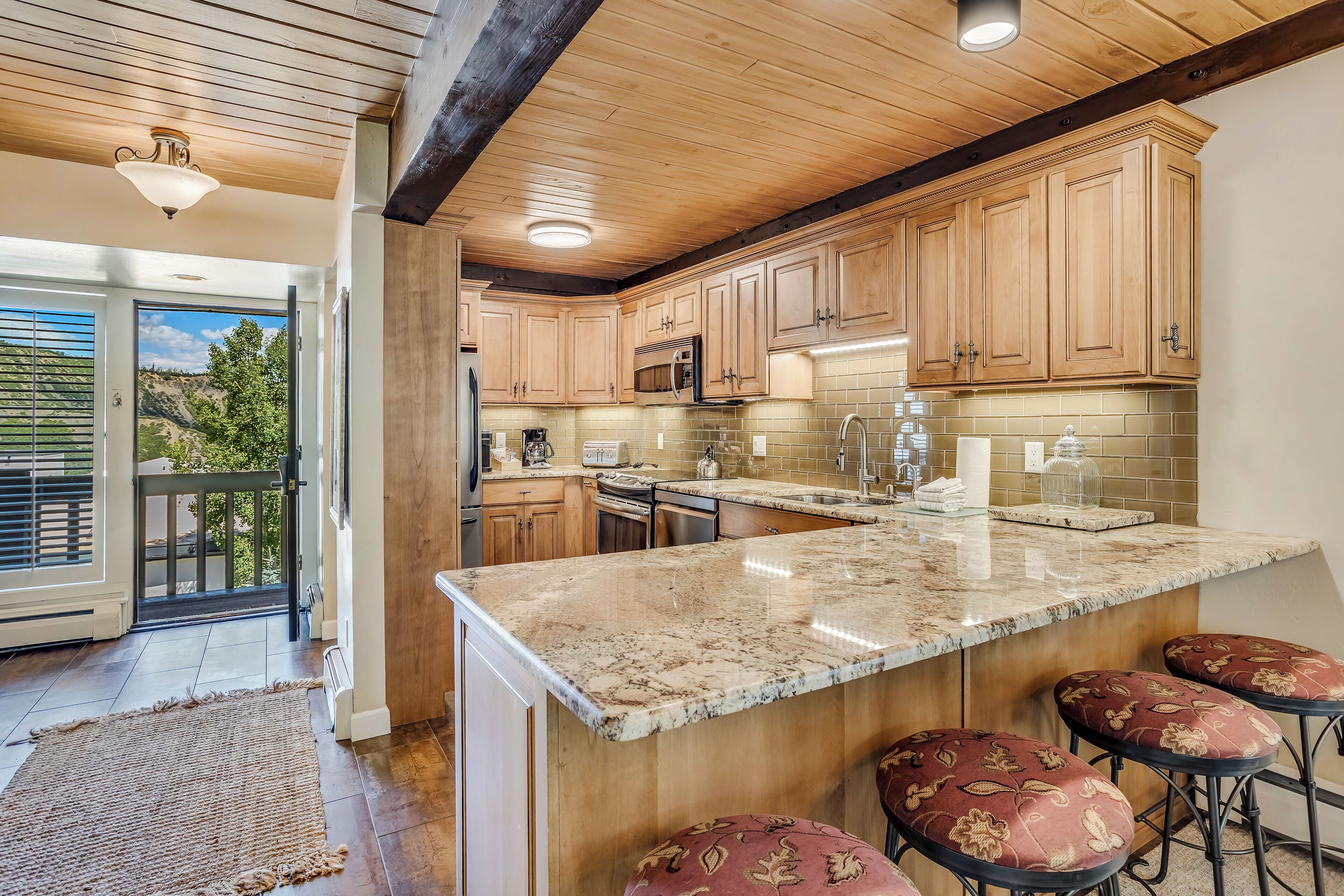 A kitchen with wooden cabinets, a granite countertop, and a built-in island with bar stools.