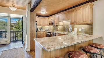 A kitchen with wooden cabinets, a granite countertop, and a built-in island with bar stools.