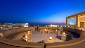 A rooftop lounge with a curved seating area, tables, and ambient lighting. - AMARANDE Adults Only (Ayia Napa)