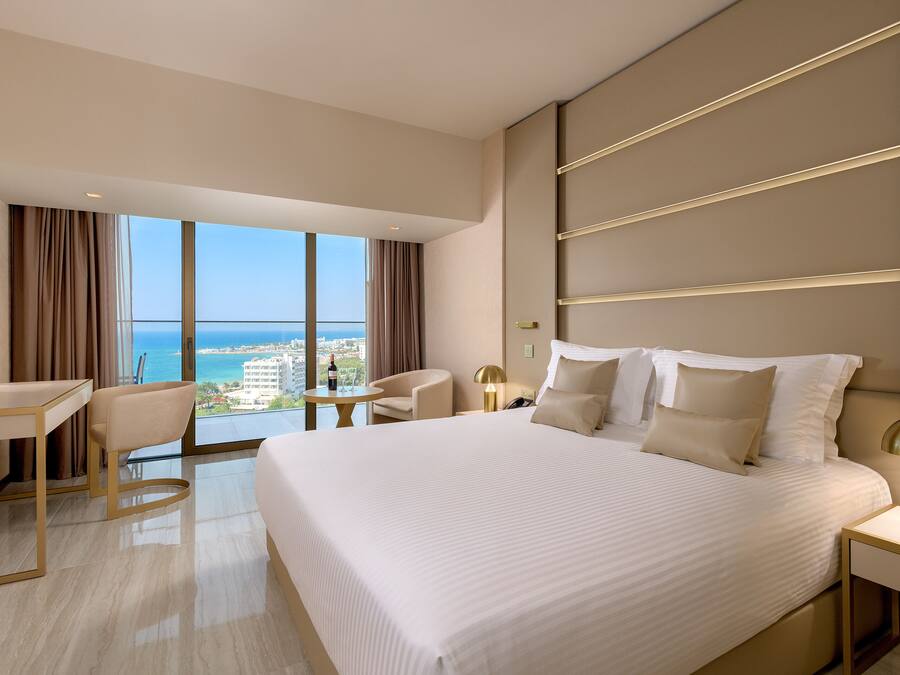 Un hotel moderno con una cama grande, un escritorio, una silla y vistas al océano.