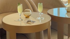A modern lounge area with round tables and comfortable seating, featuring drinks and a decorative glass sphere. - AMARANDE Adults Only (Ayia Napa)