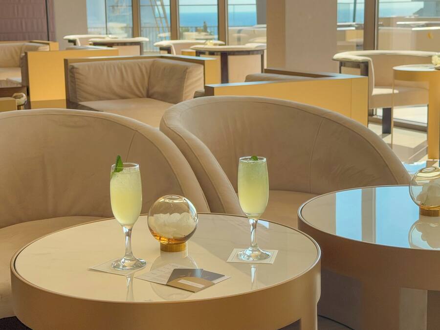 Un espace lounge moderne avec des tables rondes et des sièges confortables, où l’on sert des boissons, et agrémenté d’une sphère de verre décorative.