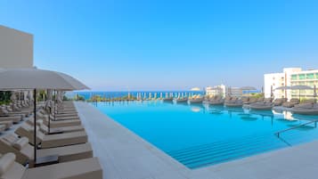 Una piscina cubierta, una piscina al aire libre, sombrillas, tumbonas