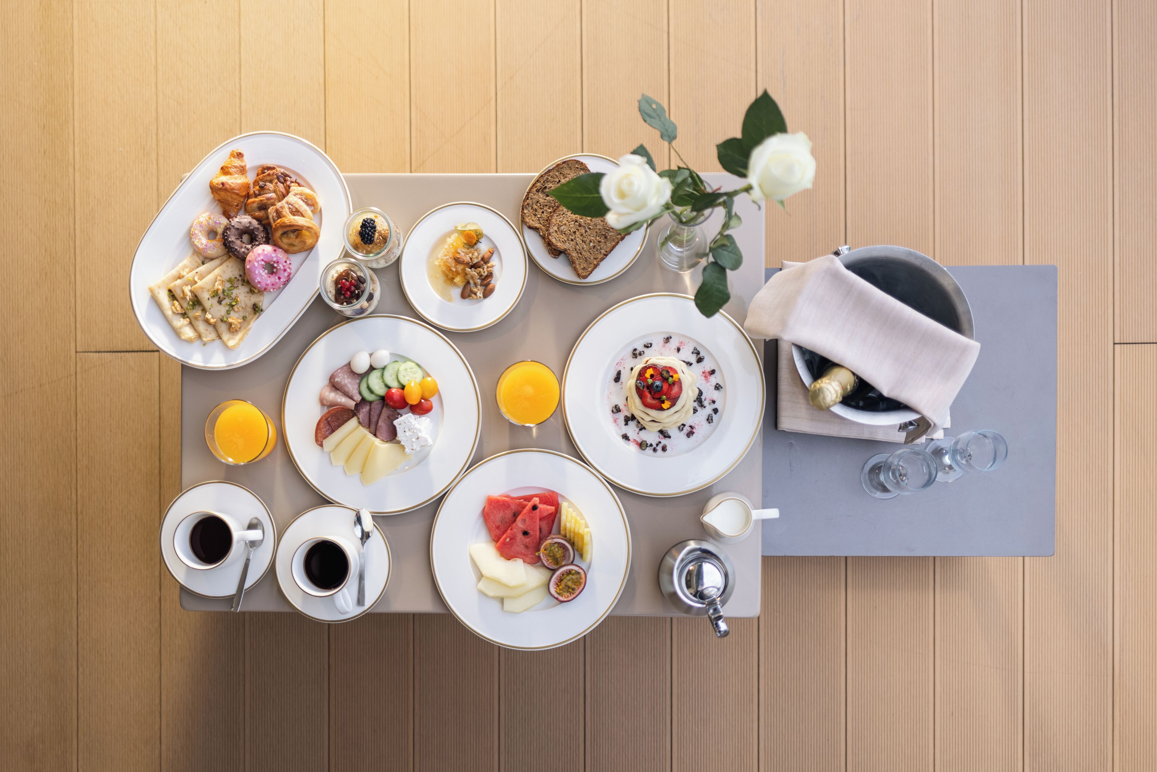 Ein reichhaltiges Frühstücksbuffet mit Speisen, Getränken und einer Blumenvase auf einem Holztisch.