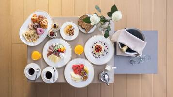 Ein reichhaltiges Frühstücksbuffet mit Speisen, Getränken und einer Blumenvase auf einem Holztisch.