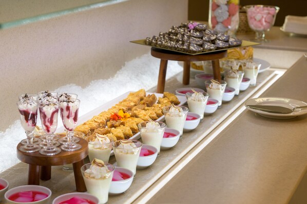 A buffet table with various desserts and beverages.