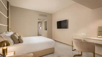A modern hotel room with a large bed, a desk, and a chair. There is a television on the wall and a power outlet on the desk.