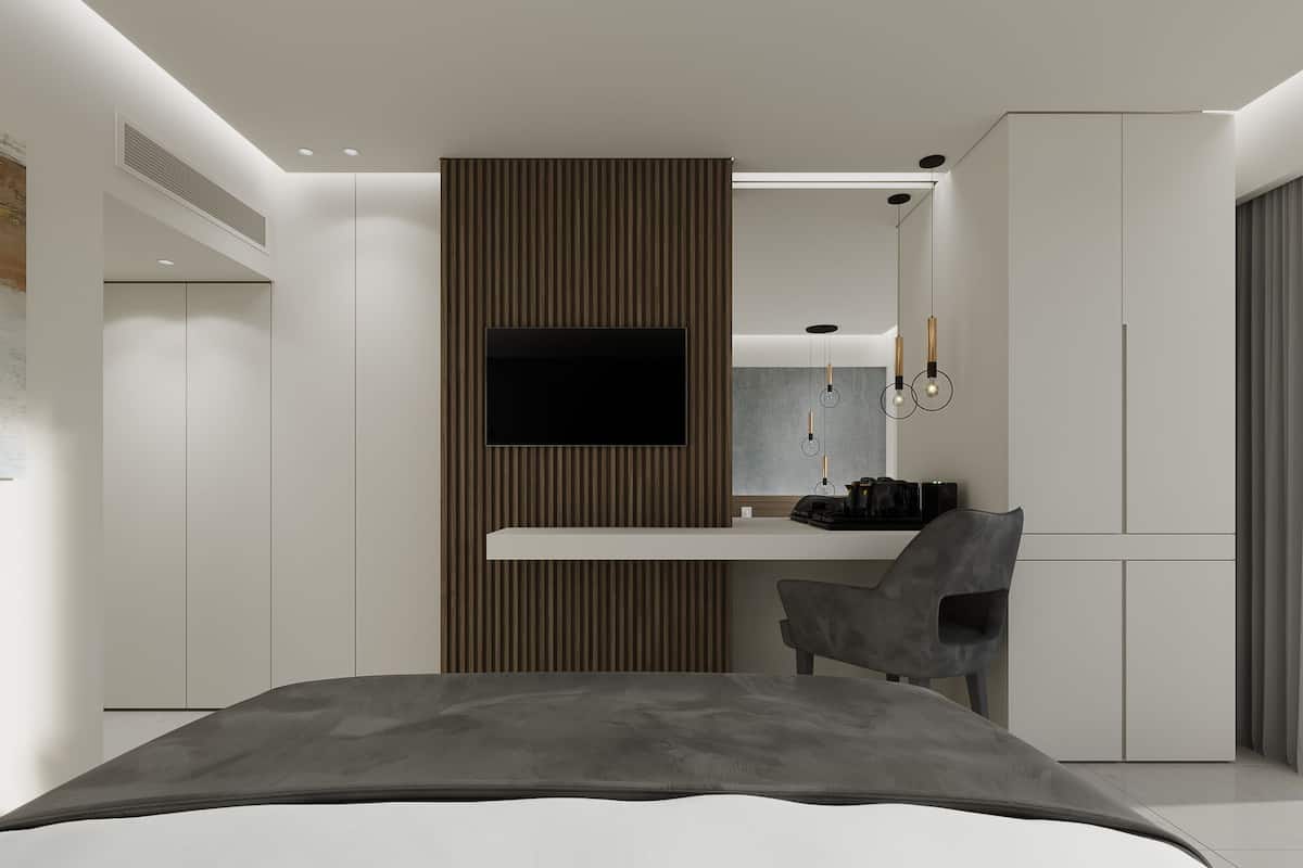 Un dormitorio moderno con cama, escritorio con silla, televisor y armario.