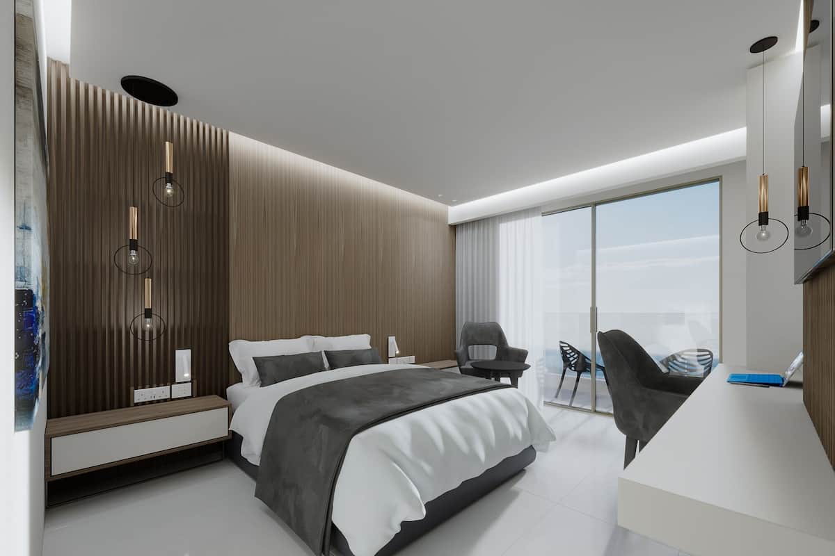Una habitación de hotel moderna con una cama grande, un escritorio y un balcón con sillas.