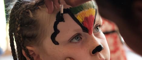 A person painting a face with a brush.