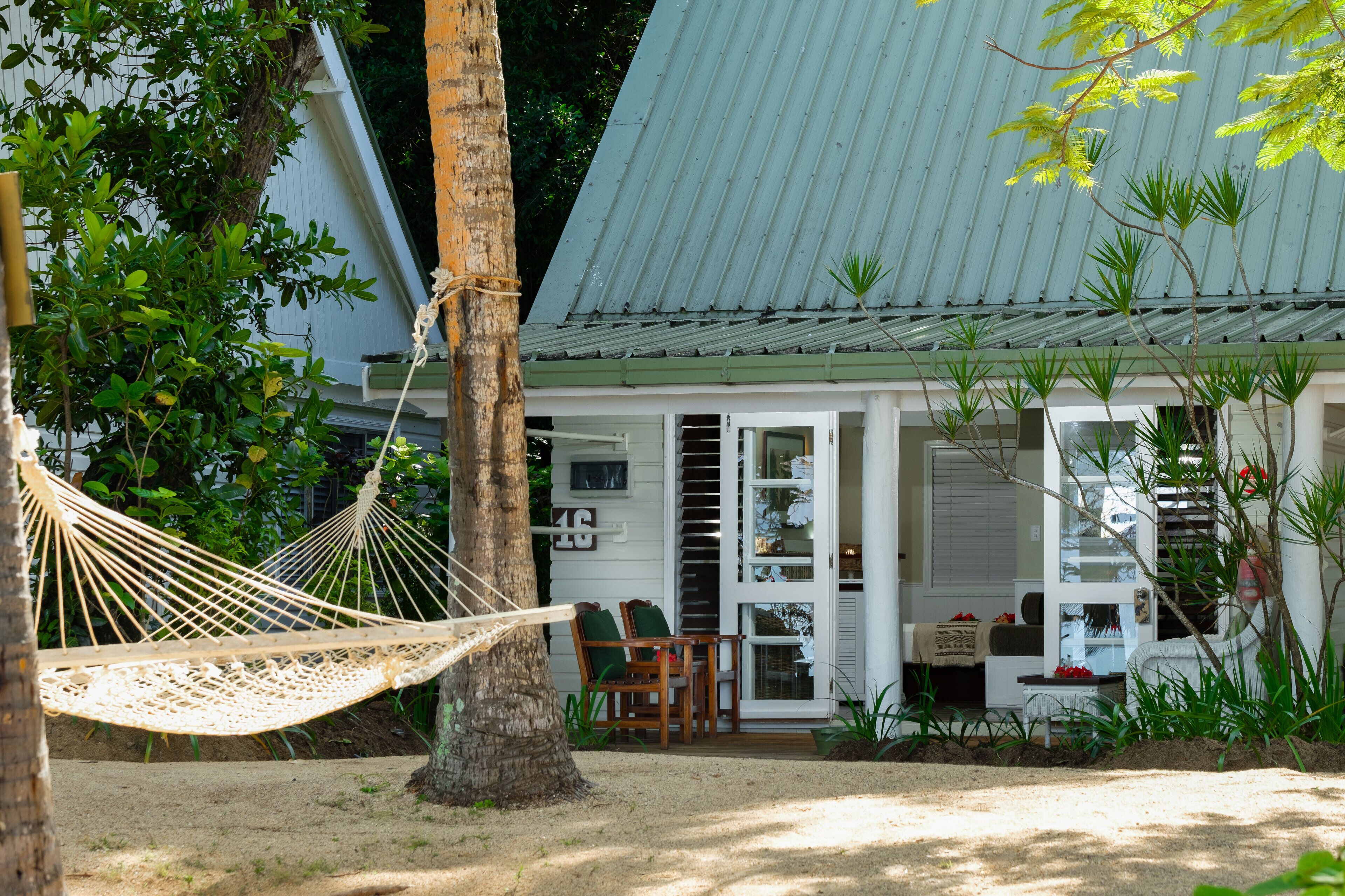 A house with a porch, a hammock, and a small outdoor seating area.