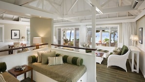 A spacious living area with a high ceiling, built-in seating, and large windows offering a view of the outdoors. - Malolo Island Resort (Malolo Island)