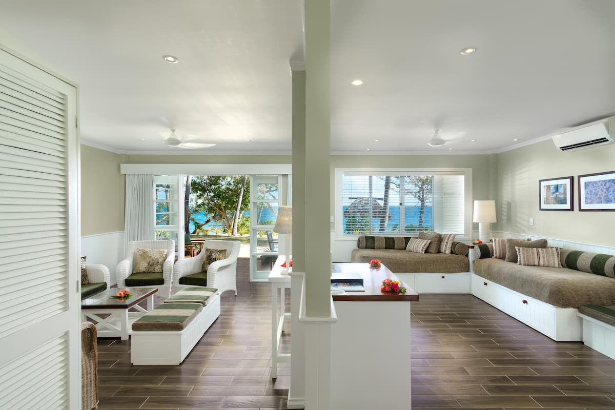 Un salón amplio con un gran ventanal, muebles blancos y vistas al exterior.