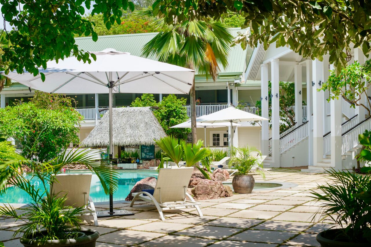 A poolside area with lounge chairs, umbrellas, and a thatched roof structure.