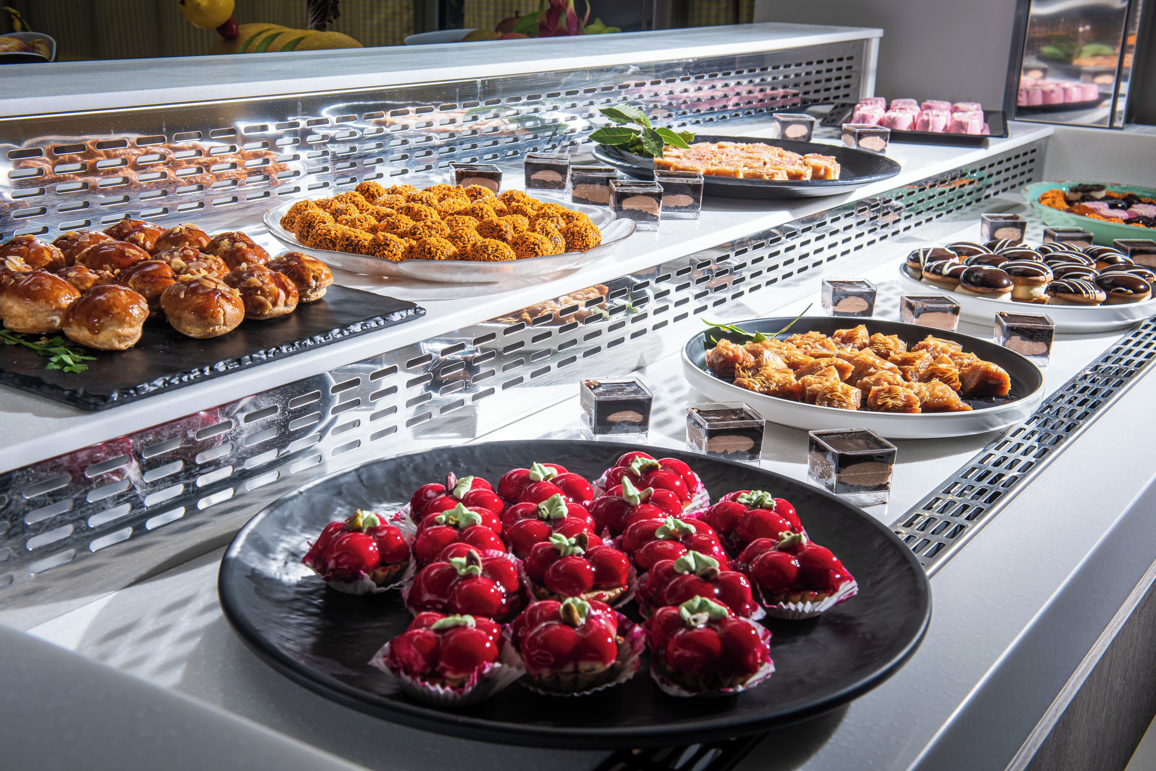A buffet with various food items including pastries, desserts, and fruit.