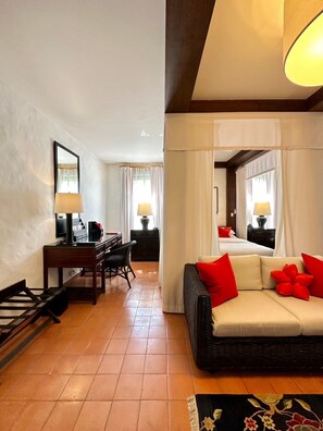 Relax in a stylish room with a comfortable sofa, desk, chair, and bed, surrounded by a large mirror and natural light.