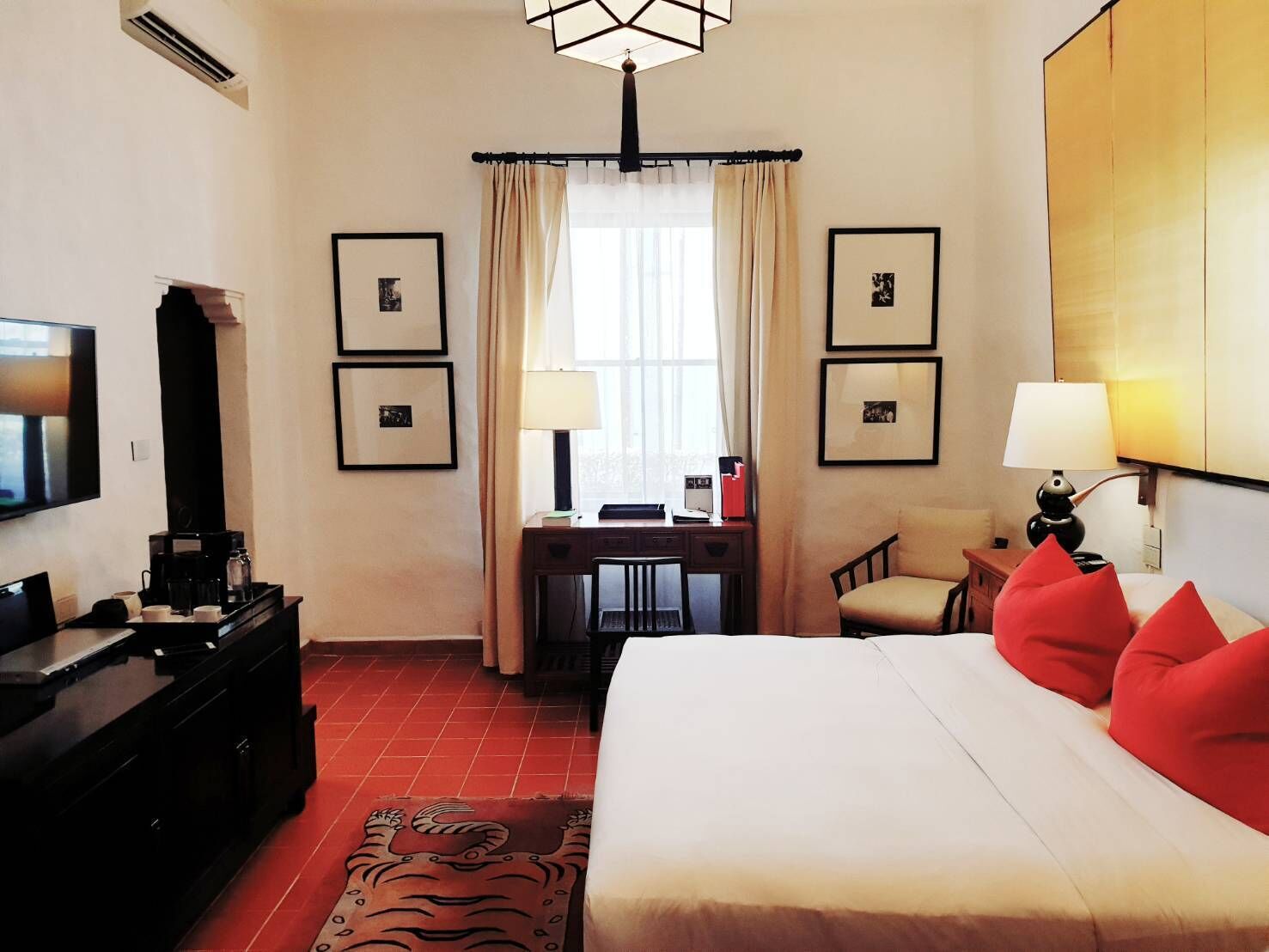 Una habitación de hotel con cama, escritorio, silla, televisión y cafetera.