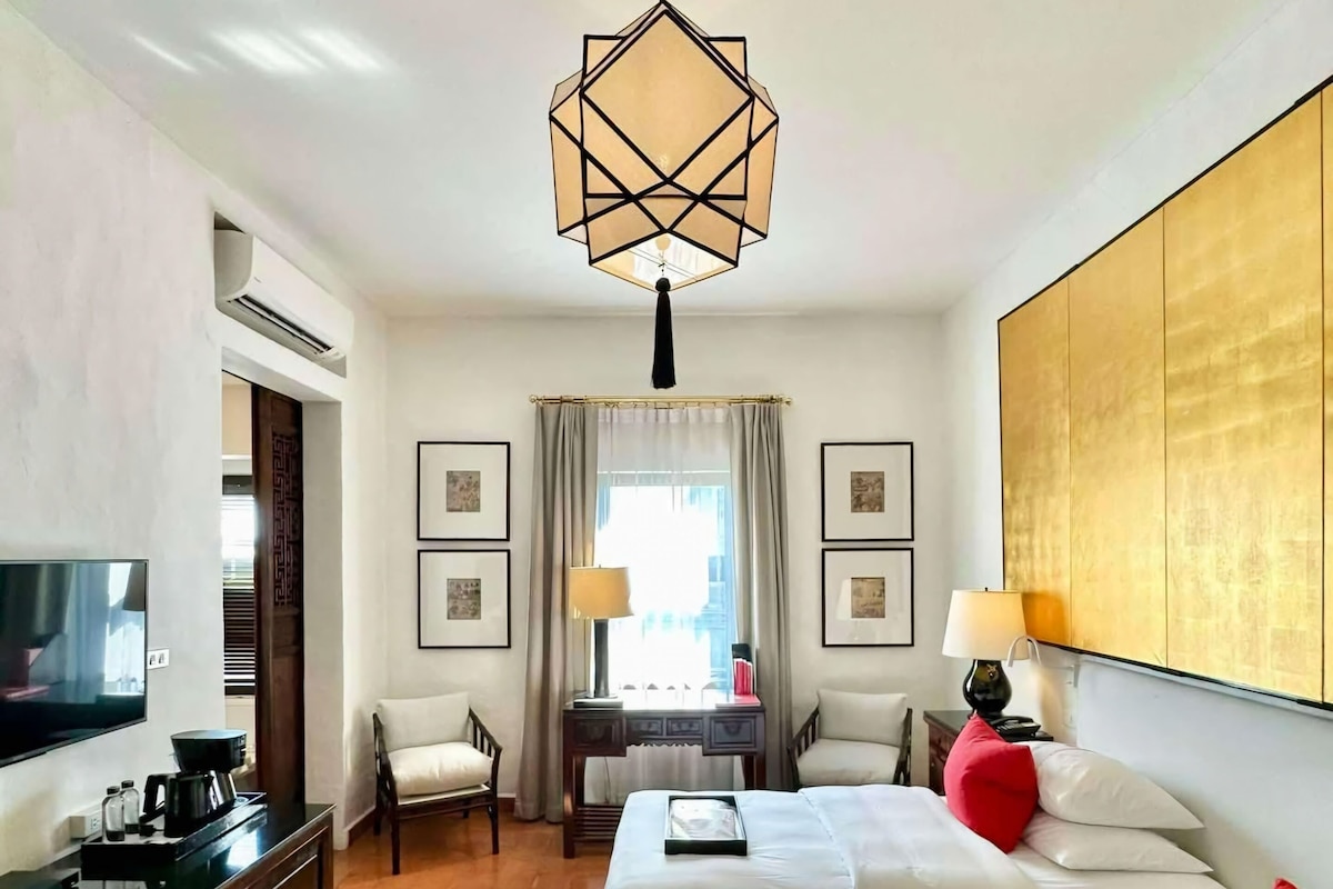 A hotel room with a large bed, a desk, a television, and a decorative rug.