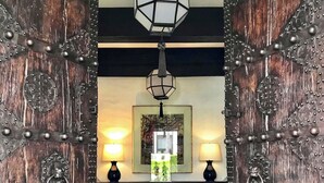 A rustic wooden door with metal studs and a hanging lantern. - Rachamankha Hotel (Chiang Mai)
