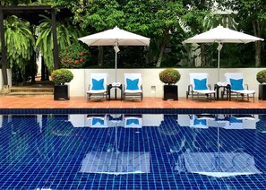 Relax by the serene pool surrounded by lush greenery and comfortable lounge chairs.