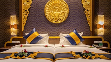 Ett lyxigt hotellrum med en stor säng, en utsmyckad sänggavel och ett dekorativt emblem ovanför sängen.