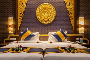 Ett lyxigt hotellrum med en stor säng, en utsmyckad sänggavel och ett dekorativt emblem ovanför sängen.