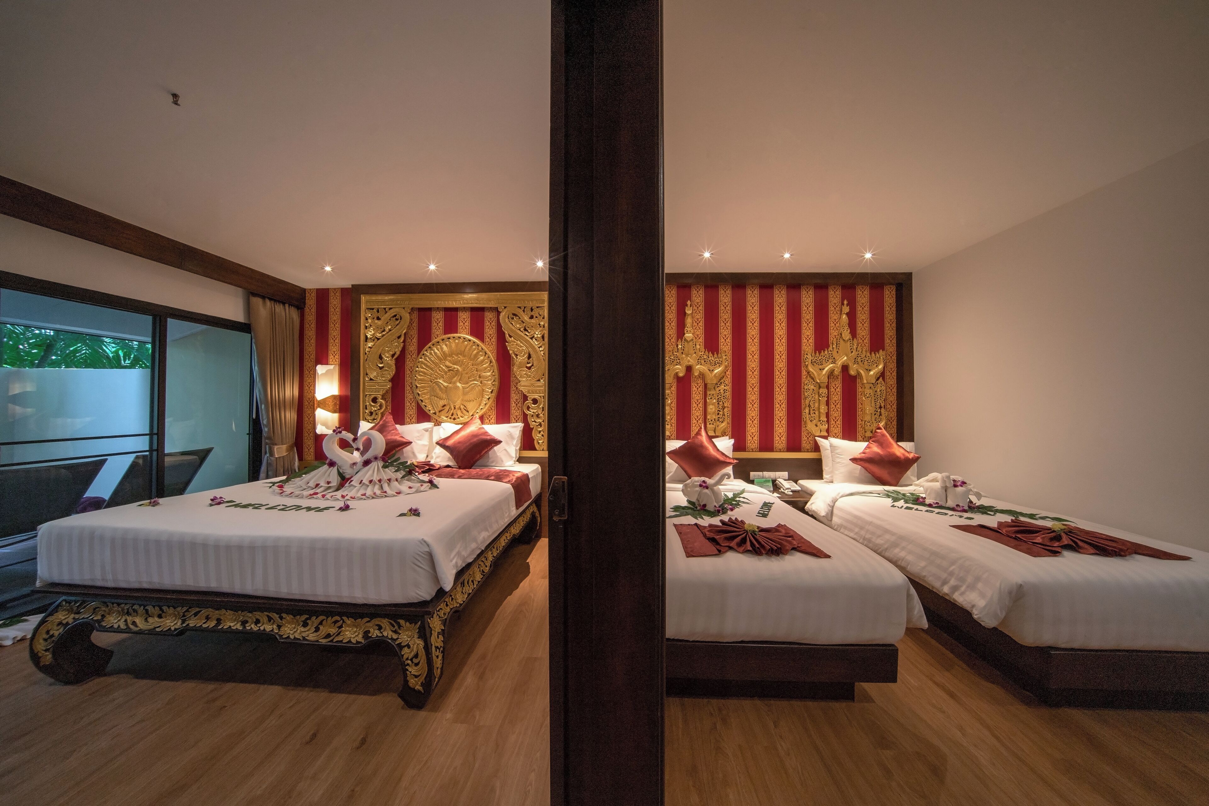 Una habitación de hotel con dos camas, un ventanal grande y un revestimiento decorativo con motivos dorados.