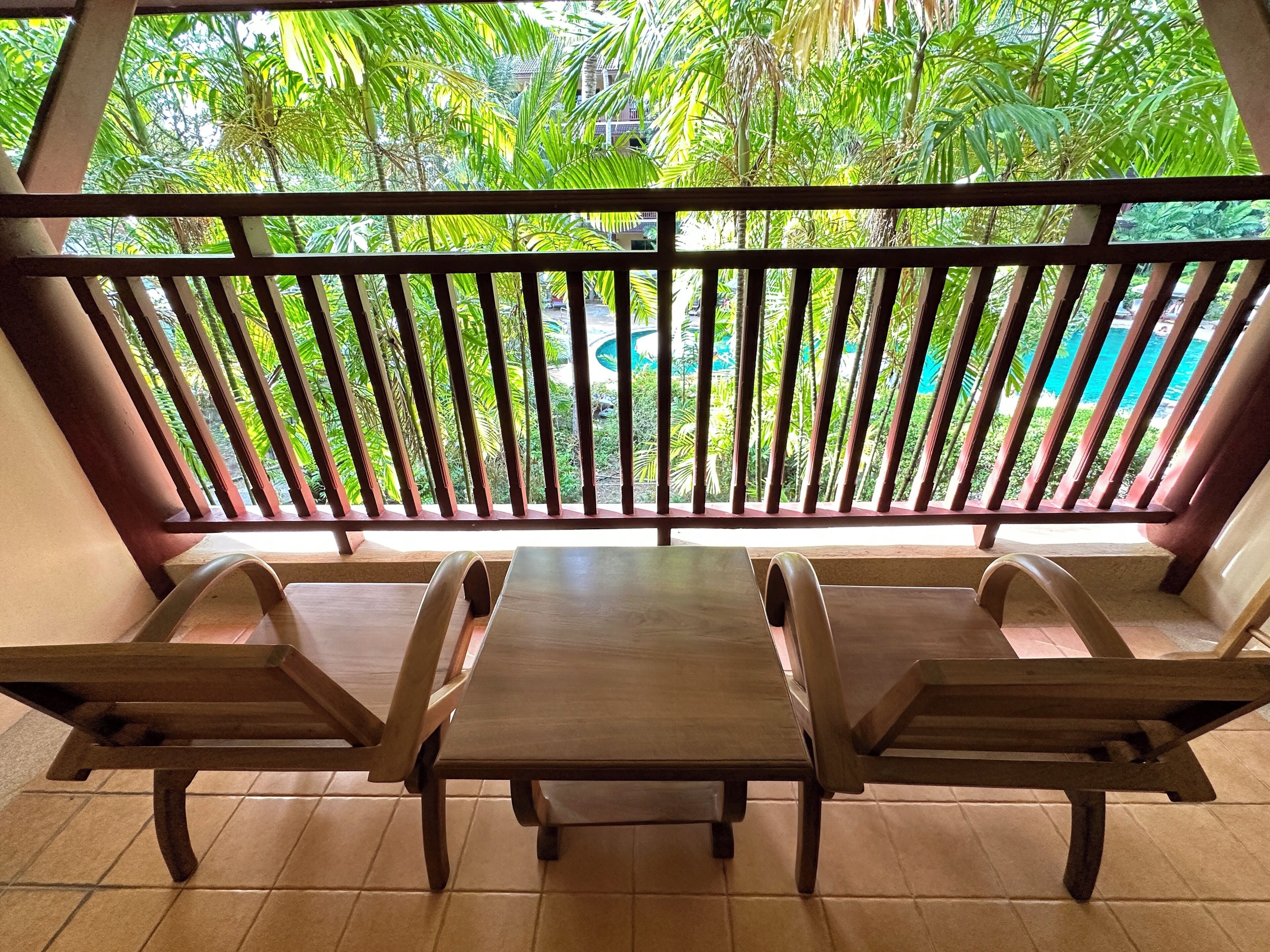 Un balcon doté de mobilier en bois et offrant une vue sur une végétation luxuriante.