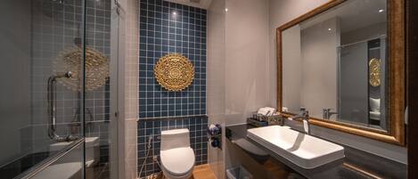 A modern bathroom with a glass-enclosed shower, a white toilet, and a large mirror with a decorative frame.