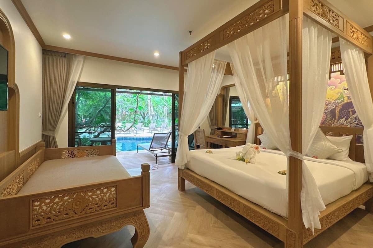 Una cama con dosel tradicional, un mesita de noche de madera y vista a un área de piscina al aire libre.