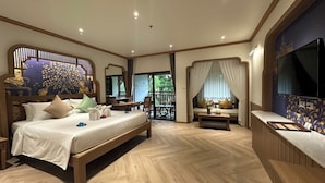 A spacious bedroom with a large bed, a desk, a seating area with a view, and a television.