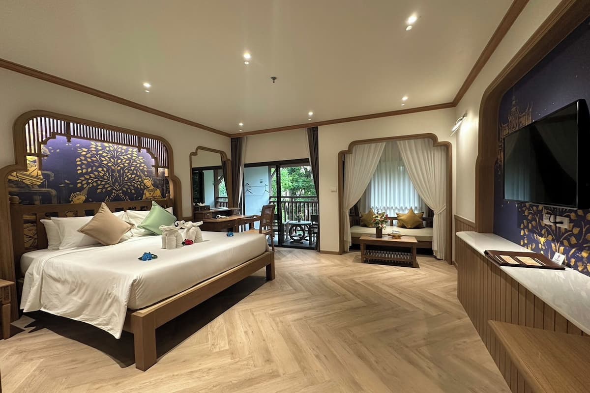 Un dormitorio espacioso con una cama grande, un escritorio, una zona de estar con vistas y un televisor.