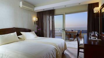 A hotel room with a large bed, a balcony with a dining table, and a view of the city skyline.