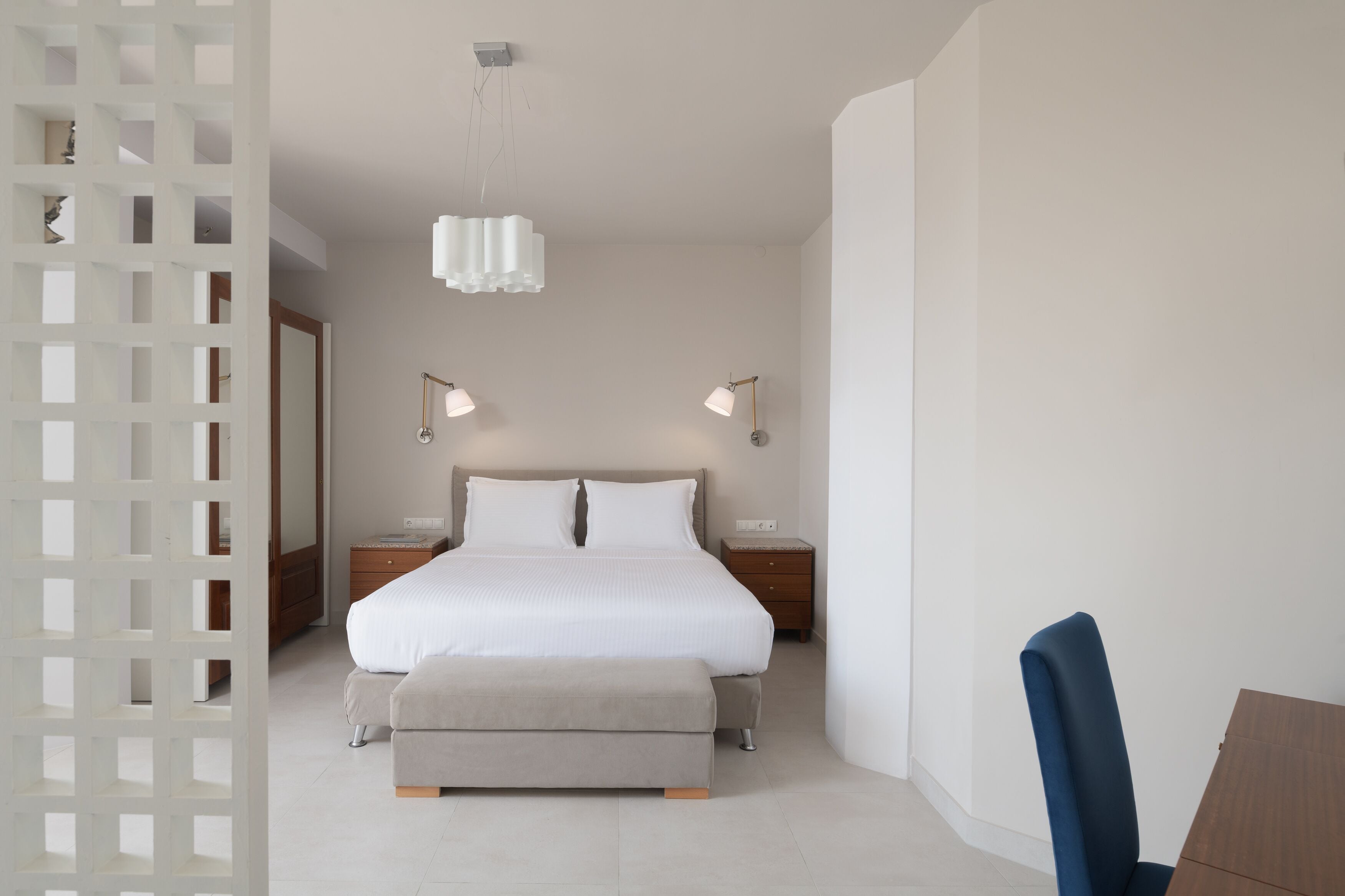 Ein modernes Schlafzimmer mit einem großen Bett, Nachttischen und einem Sessel.